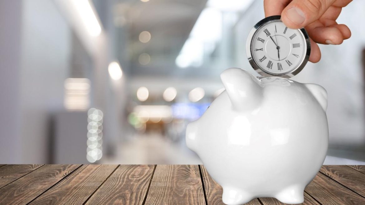 Une main déposant une horloge dans une tirelire en forme de cochon, illustrant l'importance du temps dans la gestion de son patrimoine