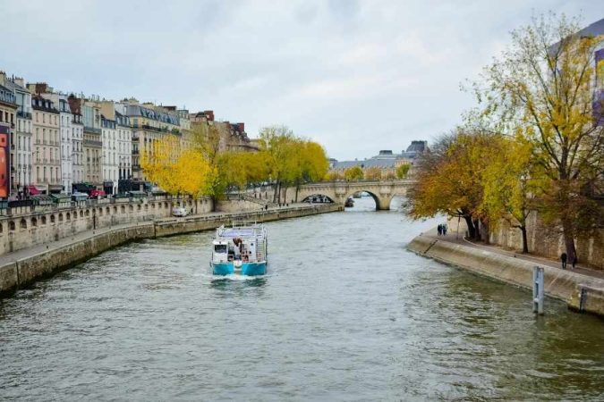 Une bateau navigue sur la Seine à Paris, une destination prisée des voyageurs francophones en automne.