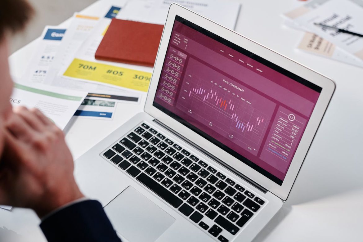 Un investisseur en costume analyse un graphique boursier complexe sur son ordinateur portable, réfléchissant à des Contrats d'options, entouré de documents financiers sur son bureau.